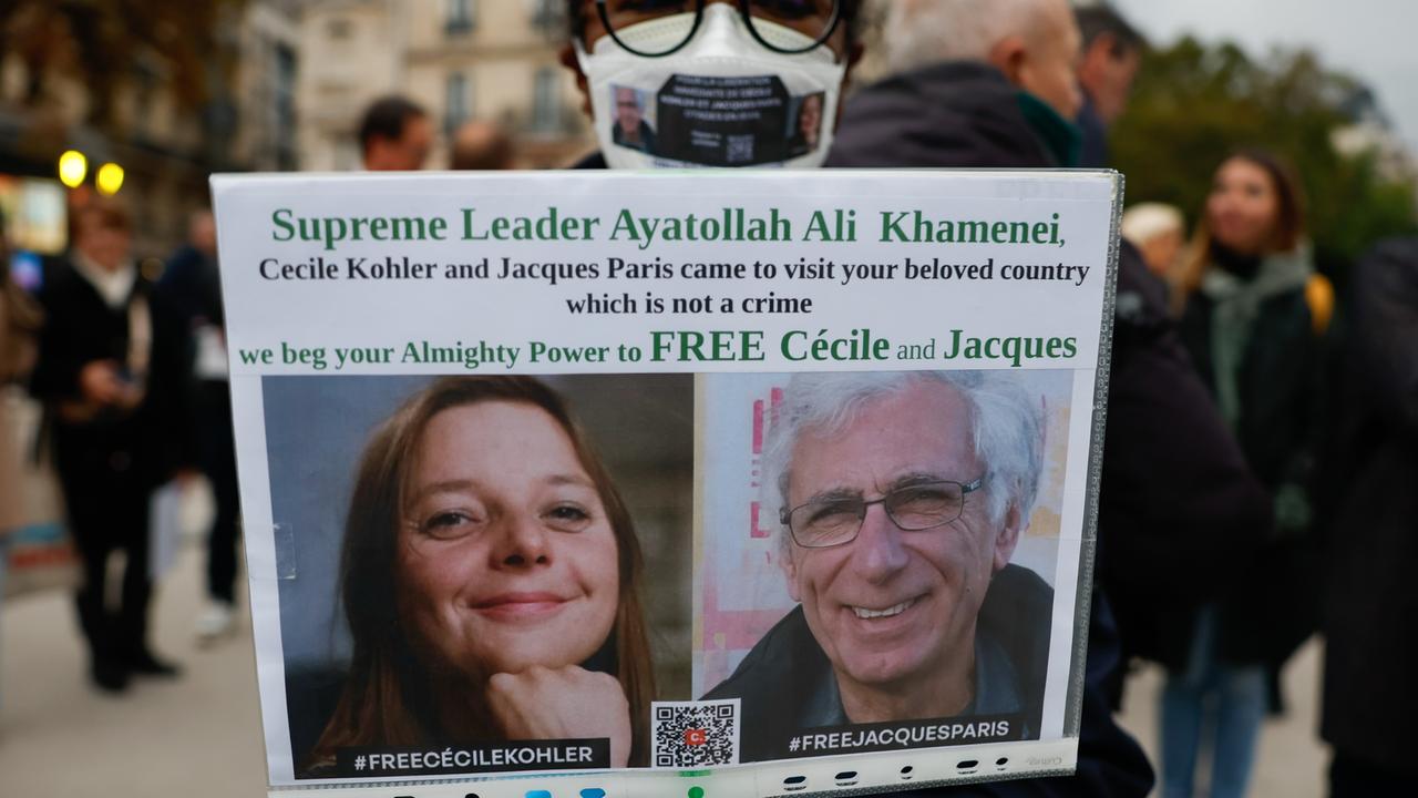 Eine Frau hält ein Plakat mit einem Bild von Cécile Kohler und Jacques Paris, die im Mai 2022 während einer Touristenreise in den Iran verhaftet wurden.