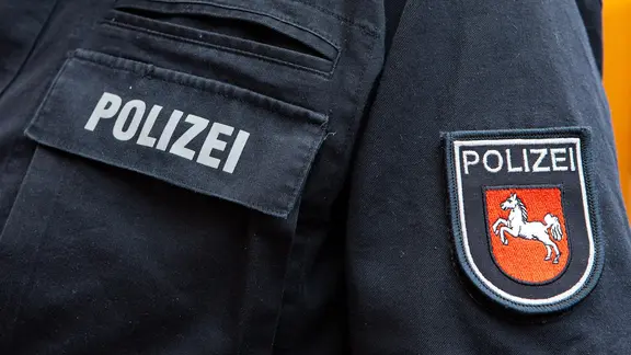 Der Schriftzug "Polizei" und das Niedersachsen-Pferd auf einer Polizeiuniform.
