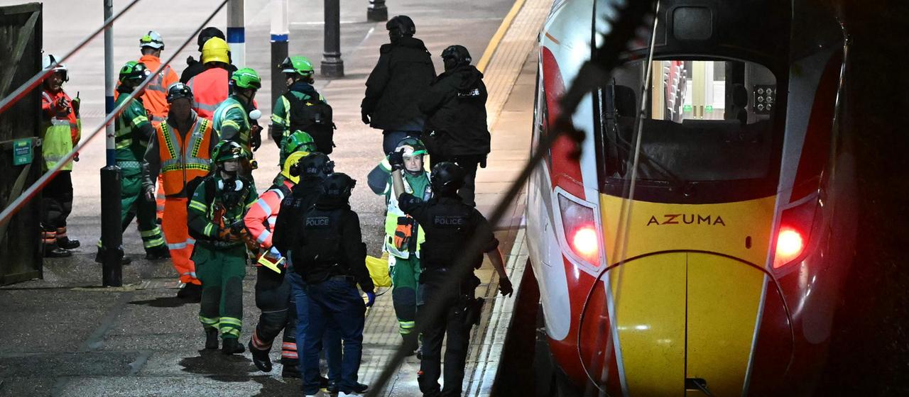 Polizisten und Rettungskräfte stehen neben einem Zug am Bahnhof