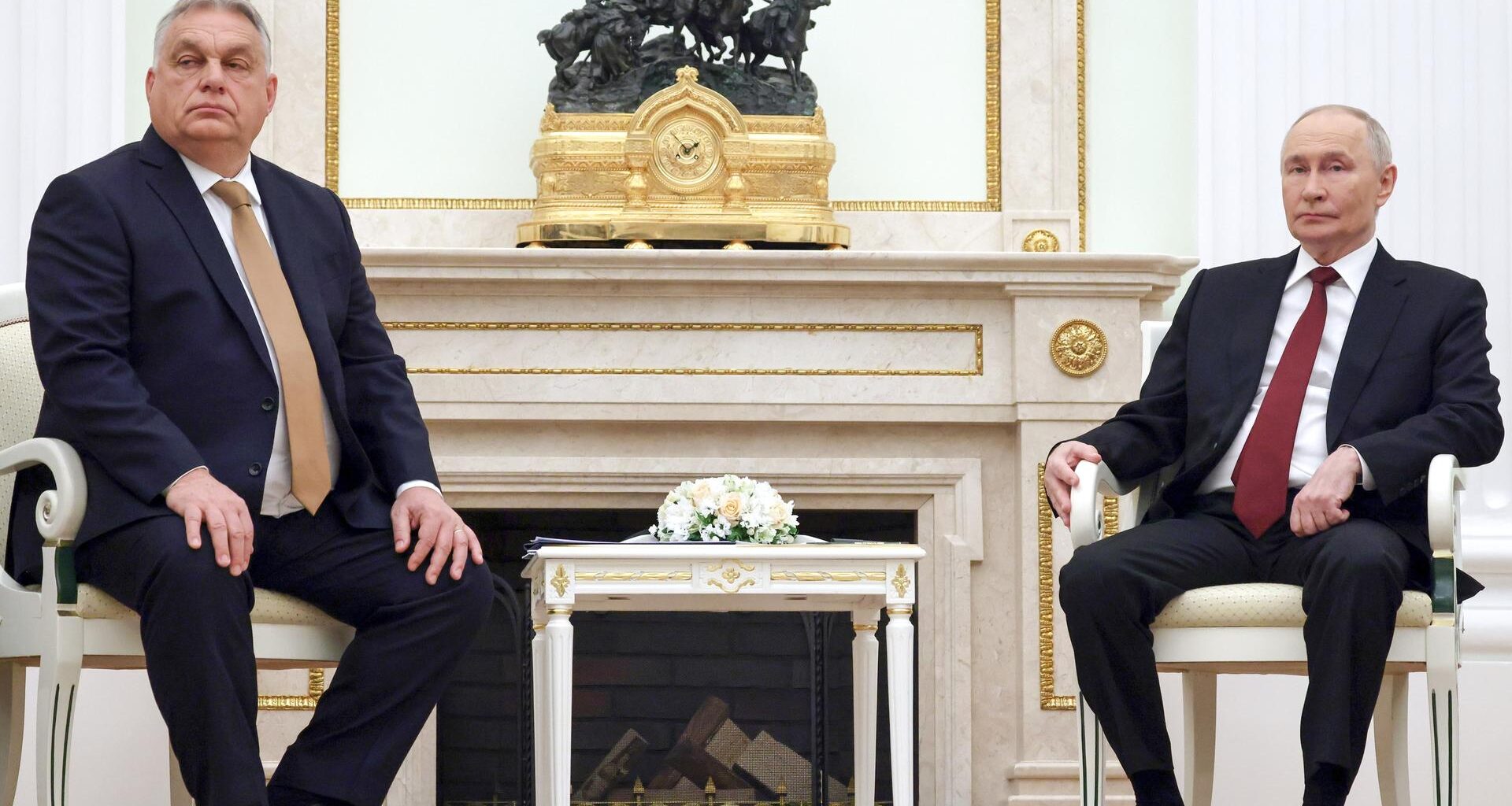 Orban und Puten sitzen nebeneinander auf Stühlen, zwischen ihnen steht ein kleiner Tisch.