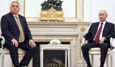 Orban und Puten sitzen nebeneinander auf Stühlen, zwischen ihnen steht ein kleiner Tisch.