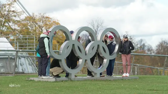 Mehrere Menschen lassen sich mit den Olympischen-Ringen ablichten.