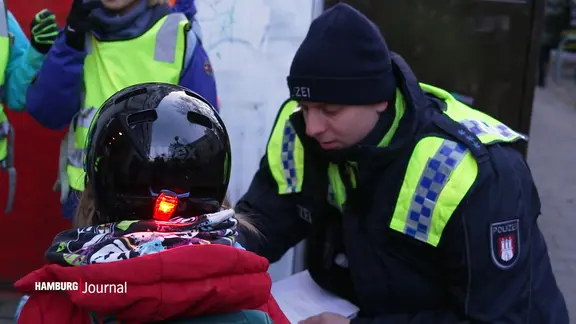 Ein Polizist spricht mit einem Kind mit Fahrradhelm.