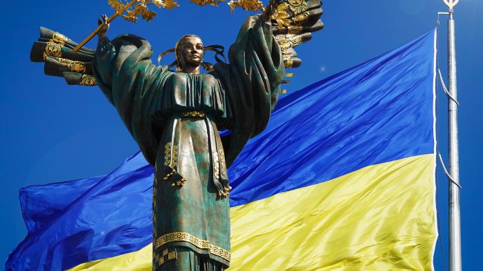 Ein Denkmal, das der Unabhängigkeit der Ukraine vor dem Hintergrund der größten Flagge der Ukraine gewidmet ist