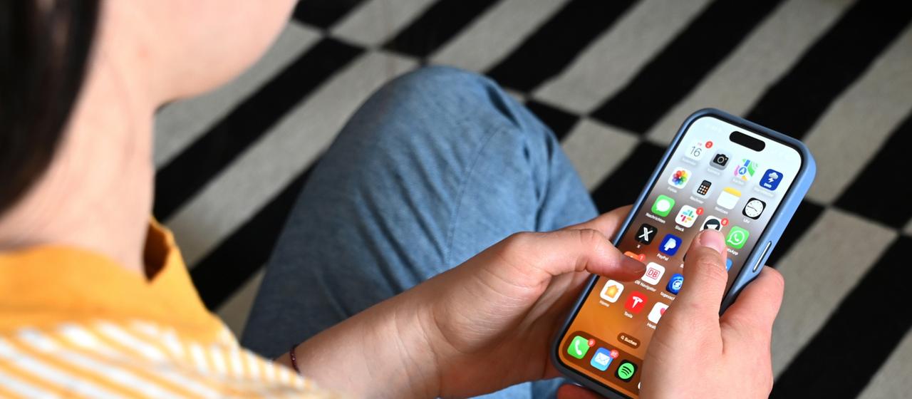 Eine Jugendliche sitzt auf dem Boden und nutzt ein Smartphone