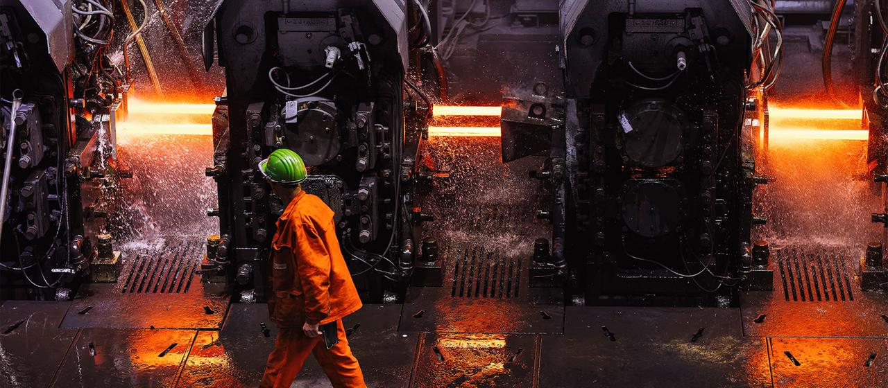 Ein Mitarbeiter der Badischen Stahlwerke GmbH (BSW) geht durch das Walzwerk der Firma.