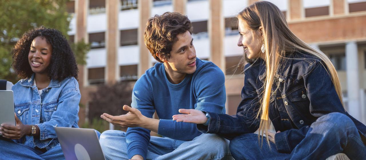 Studierende unterhalten sich auf dem Campusgelände.
