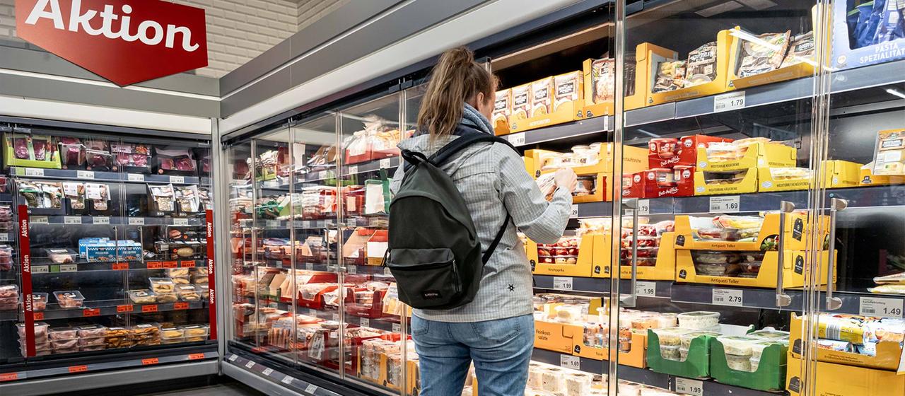 Eine Kundin steht in einem Supermarkt vor dem Kühlregeal. | picture alliance/dpa Eine Kundin steht in einem Supermarkt vor dem Kühlregeal.