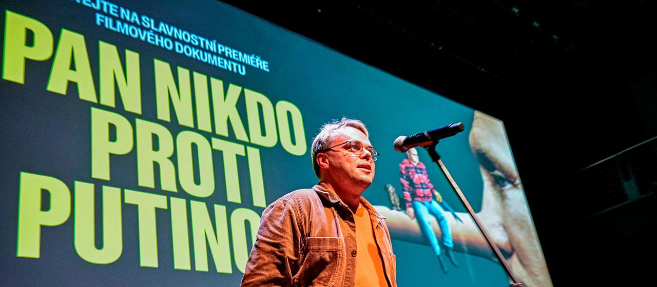 Pavel Talankin spricht vor dem Filmplakat "Mr. Nobody Against Putin". | IMAGO/CTK Photo Pavel Talankin spricht vor dem Filmplakat "Mr. Nobody Against Putin".