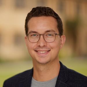 Tim Heinkelmann-Wild trägt eine Brille und lächelt in die Kamera | © David Fisher/Oxford University Tim Heinkelmann-Wild trägt eine Brille und lächelt in die Kamera