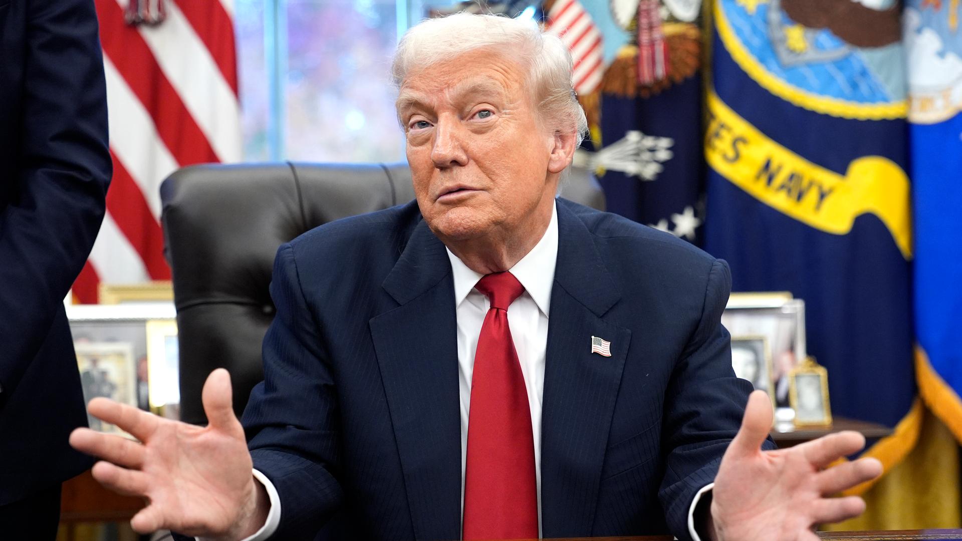 US-Präsident Donald Trump schaut abwägend. Er sitzt an seinem Schreibtisch.