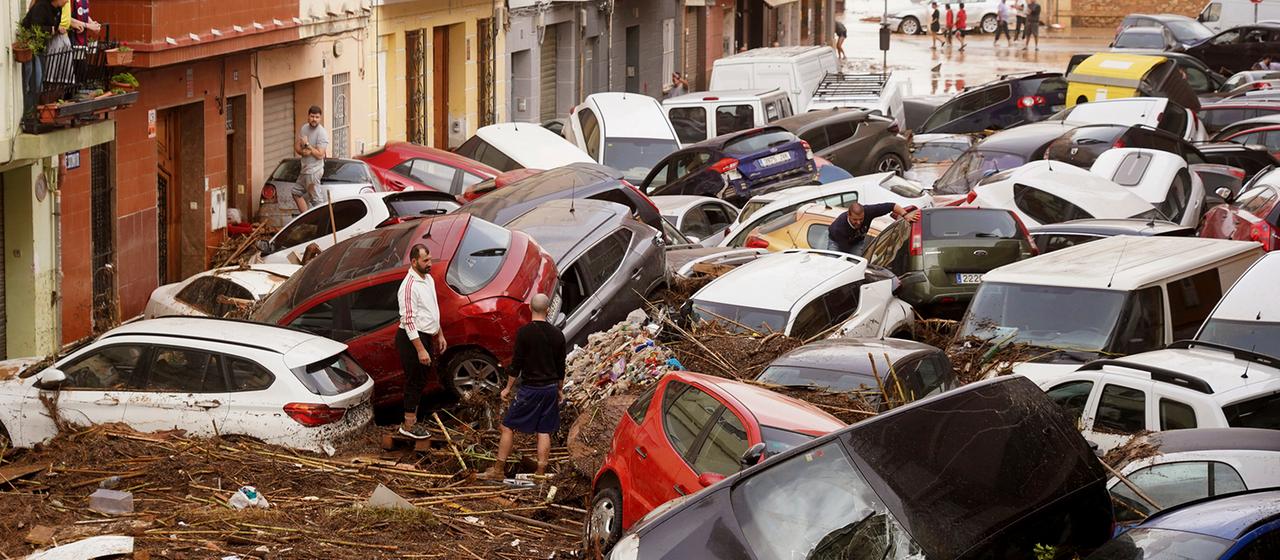 Anwohner betrachten aufgestapelte Autos, die von den Überschwemmungen in Valencia weggeschwemmt wurden. (Archivbild: 30.10.2024) | AP Anwohner betrachten aufgestapelte Autos, die von den Überschwemmungen in Valencia weggeschwemmt wurden. (Archivbild: 30.10.2024)