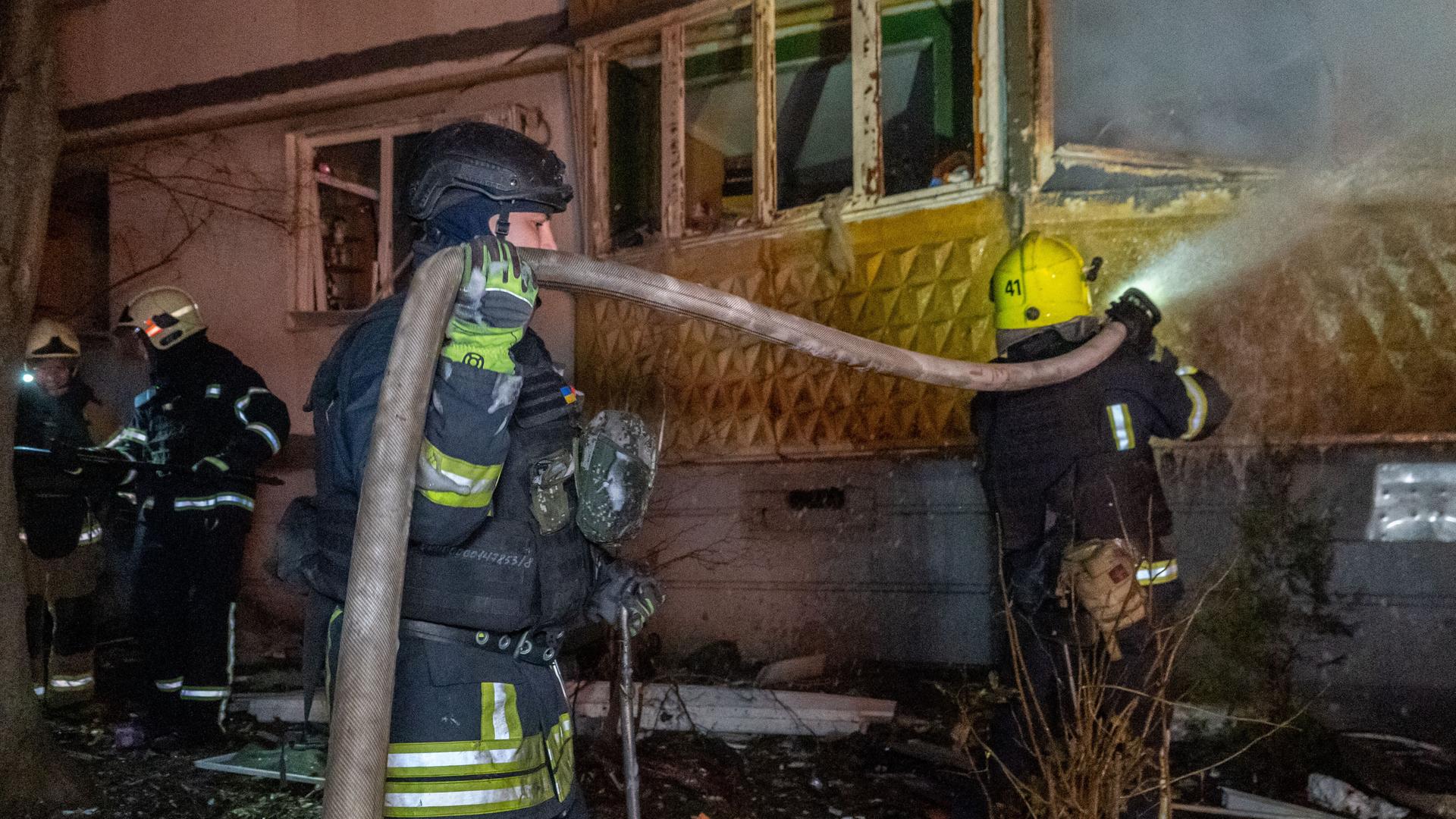 Rettungskräfte löschen ein Feuer in einem Wohnhaus in Charkiw.