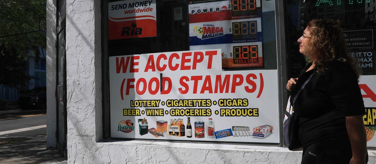 Ein Schild mit der Aufschrift "We accept (Food Stamps)" hängt an einem Ladenfenster | Getty Images via AFP Ein Schild mit der Aufschrift "We accept (Food Stamps)" hängt an einem Ladenfenster