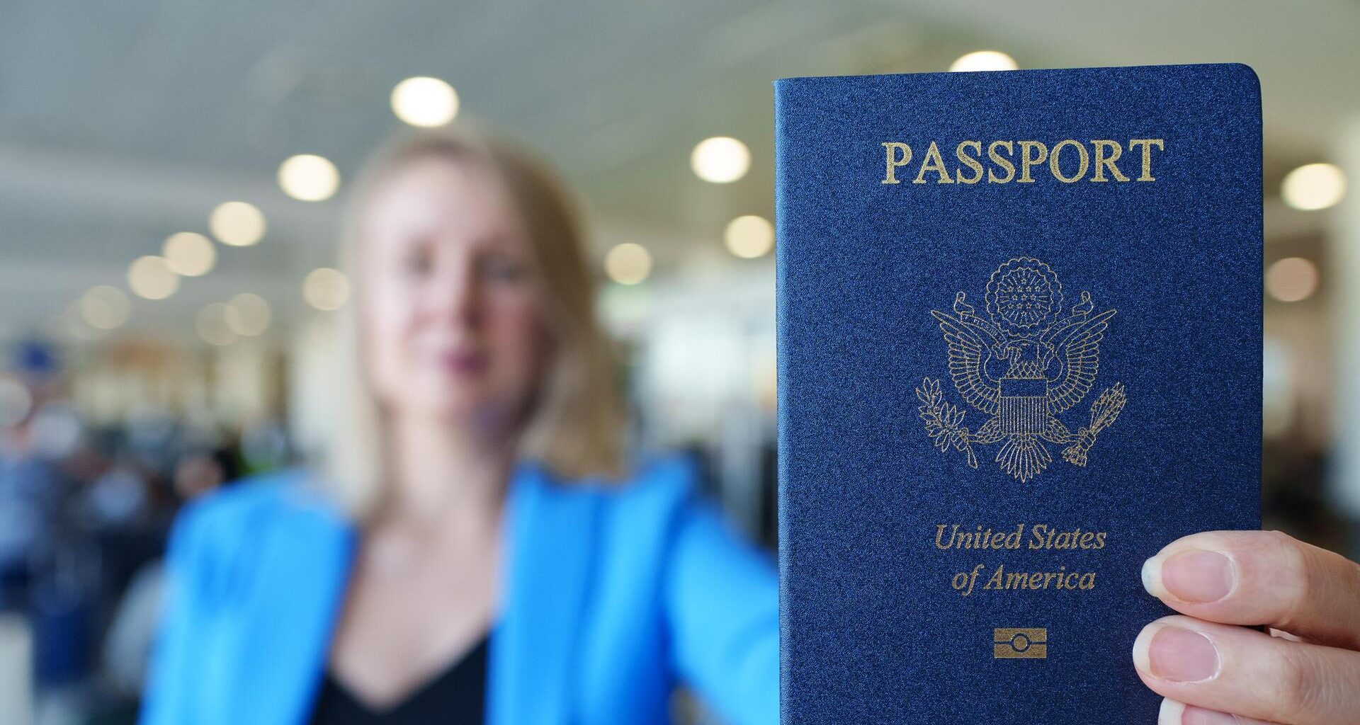 Eine Frau zeigt ihren US-amerikanischen Reisepass mit ausgestrecktem Arm.