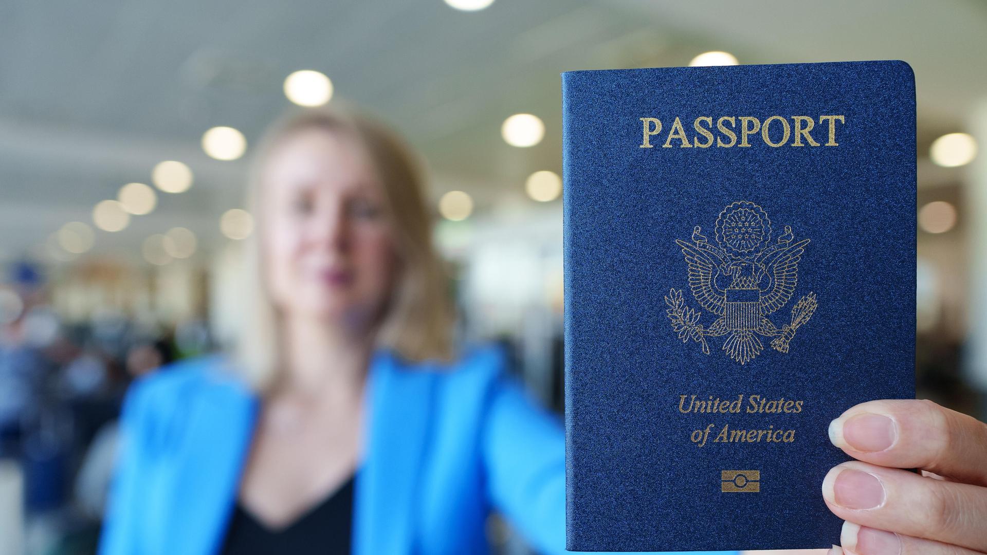 Eine Frau zeigt ihren US-amerikanischen Reisepass mit ausgestrecktem Arm.
