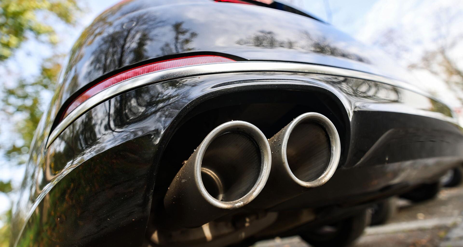 Ein Pkw mit doppeltem Auspuff steht auf einem Parkplatz. Ab 2035 sollen in der EU nur noch Neuwagen verkauft werden, die im Betrieb keine Treibhausgase ausstoßen.