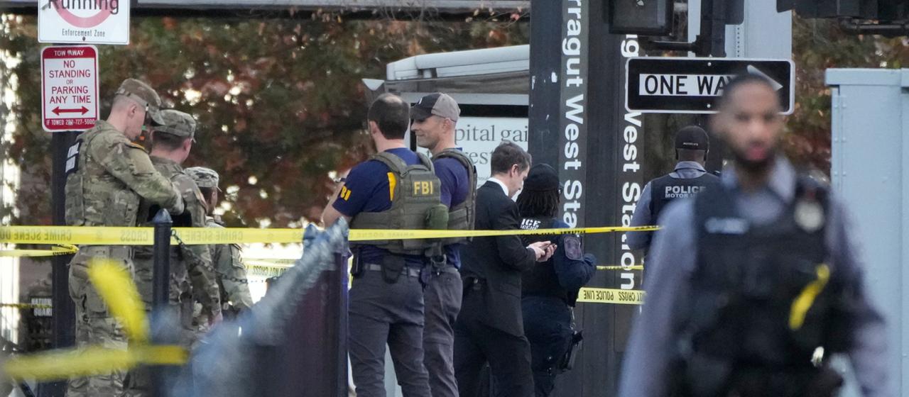 Einsatzkräfte stehen an der Stelle nahe des Weißen Hauses in Washington, wo zwei Nationalgardisten angeschossen wurden. | AP Einsatzkräfte stehen an der Stelle nahe des Weißen Hauses in Washington, wo zwei Nationalgardisten angeschossen wurden.