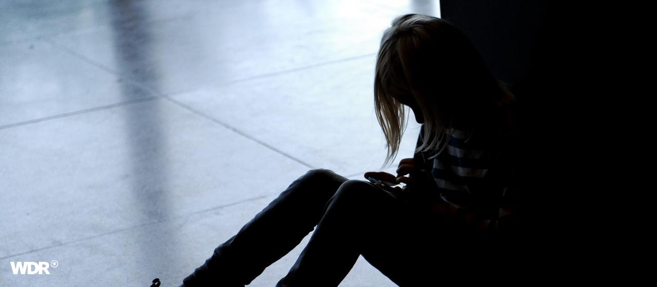 Ein kleines Mädchen sitzt allein auf dem Fußboden und hat den Kopf gesenkt