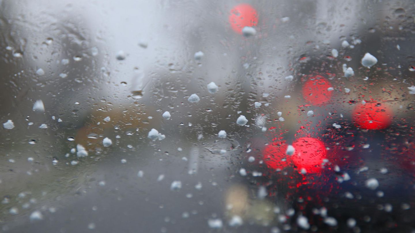 Graupelkörner und Regentropfen auf einer Windschutzscheibe. Kommende Woche muss mit nasskaltem Wetter gerechnet werden