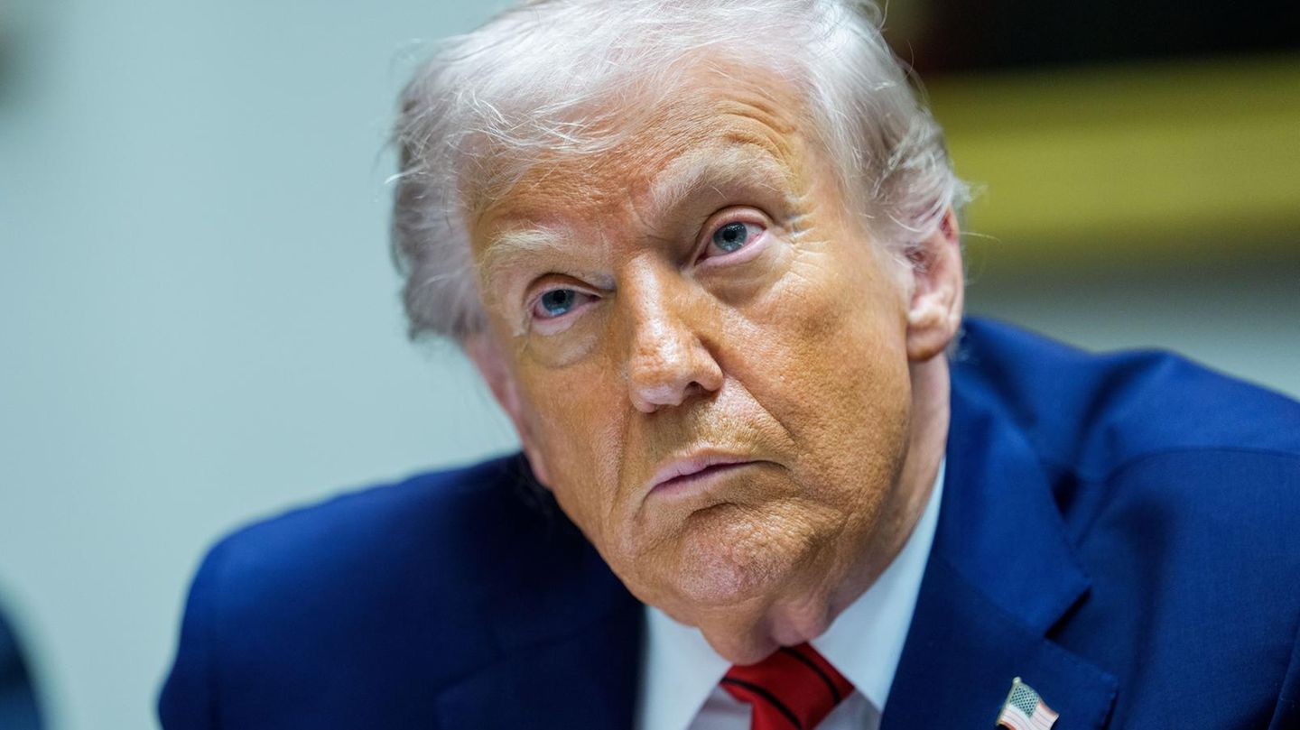 US-Präsident Donald Trump sitzt im Anzug an einem Tisch und hört zu