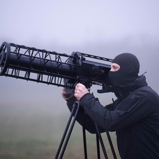 Ein maskierter Beamter nimmt eine anfliegende Drohne mit einem sogenannten Jammer ins Visier