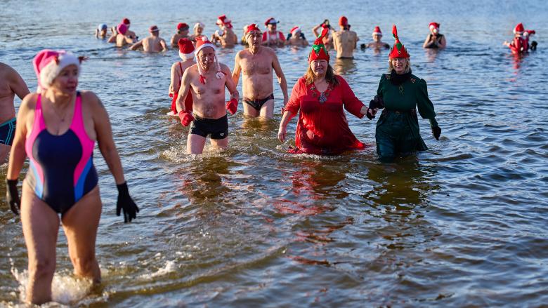 Mitglieder des Winter- und Eisschwimmvereins „Seehunde Berlin“ tragen weihnachtlich geschmückte Mützen und verlassen am Weihnachtstag den Orankensee in Berlin beim alljährlichen Weihnachtsschwimmen. (Quelle: dpa/Schreiber)