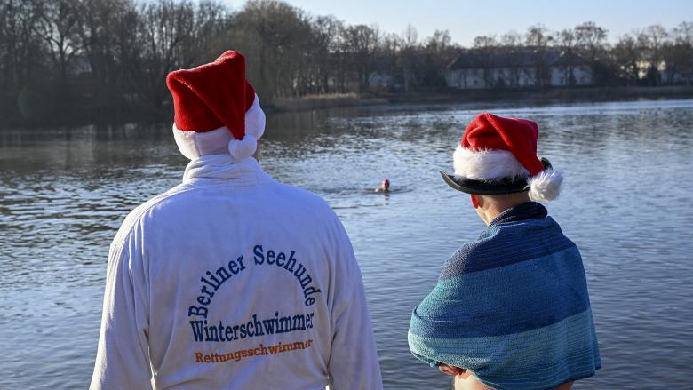 Berliner, verkleidet mit Weihnachtsmannmützen und in verschiedenen Kostümen, versammelten sich am Orankesee, um sich trotz minus acht Grad Celsius in das eisige Wasser zu stürzen. Anlass war eines der traditionellen Berliner Weihnachtsfeste, das Weihnachtsbaden, am 25. Dezember 2025. (Quelle: imago images/Sagirkaya)