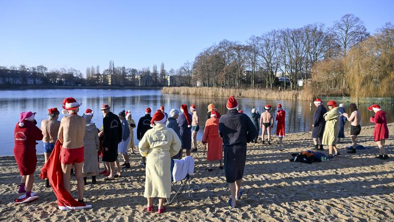 Berliner, mit Weihnachtsmannmützen und in verschiedenen Kostümen, versammeln sich am Orankesee, um sich trotz der minus 8 Grad Celsius eiskalten Wassers hinzugeben. (Quelle: dpa/Sagirkaya)