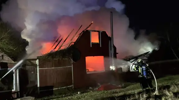 Feuerwehrleute löschen ein brennendes Wohnhaus