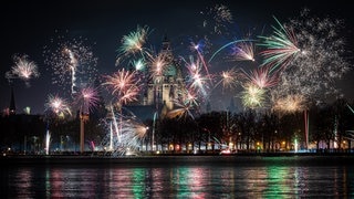 Feuerwerk explodiert in der Silvesternacht am Himmel über dem Maschsee und dem Neuen Rathaus in Hannover.