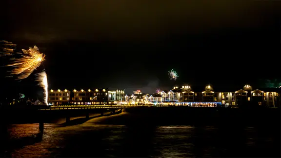 Feuerwerk am Strand mit Ferienhäusern.