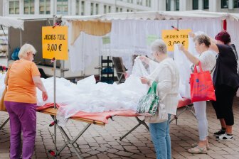 Typische Schlüpfermarktszene in Chemnitz: Seniorinnen am Wühltisch mit Gardinenstoffen.