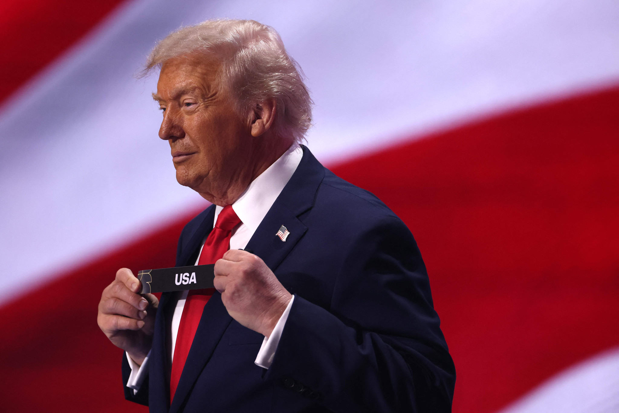 Donald Trump zieht eine Karte mit der Aufschrift ’USA’ während der FIFA-Weltmeisterschaftsauslosung 2026 im Kennedy Center in Washington, DC, vor einer US-Flagge.