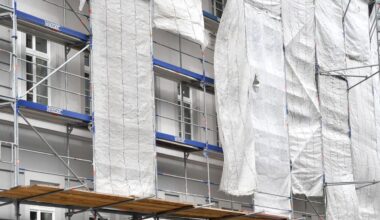 Ein Haus in München ist eingerüstet, am Gerüst hängen Planen und verdecken die Fassade zum Teil.