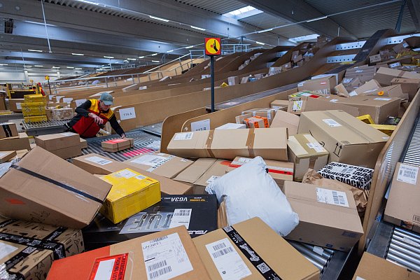 Mitarbeiter im DHL-Verteilzentrum sortieren Pakete inmitten des vorweihnachtlichen Ansturms. - © picture alliance/dpa