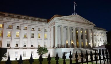 Man sieht die beleuchtete Vorderfront des Gebäudes in der Dunkelheit.