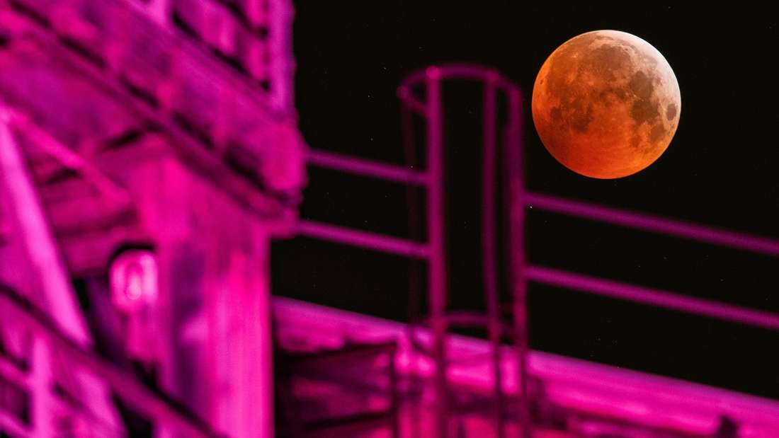Der „Blutmond” neben einem angestrahlten Hochofen im Landschaftspark Duisburg am 21. Januar 2019.