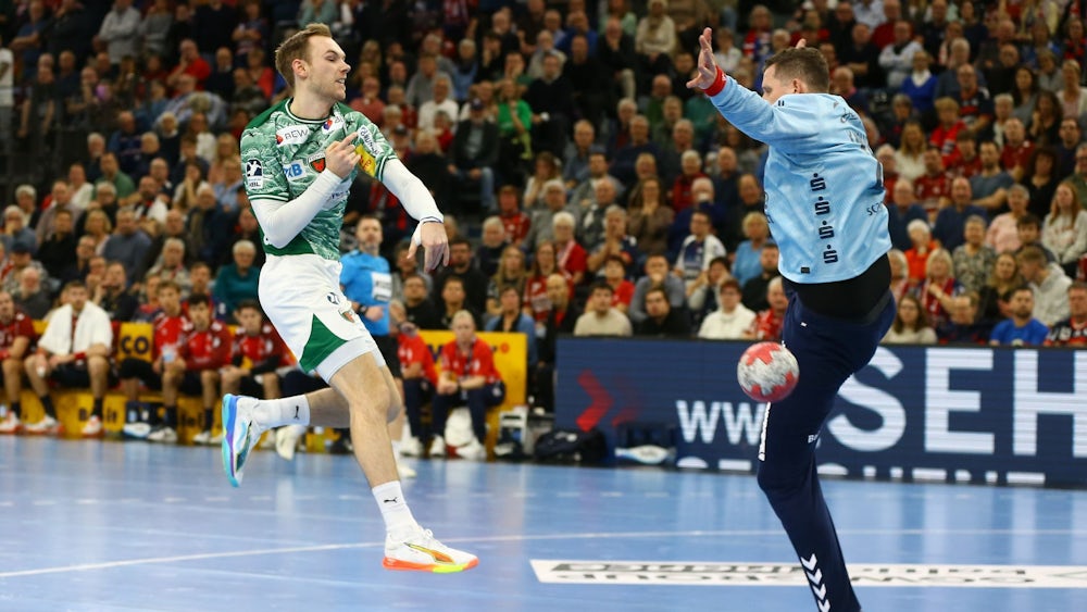 Mathias Gidsel (Füchse Berlin, l) wirft gegen den Flensburger Torwart Kevin Möller.