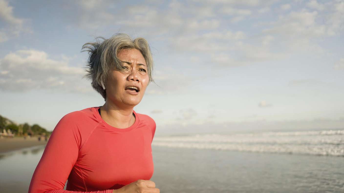 Fitte ältere Frau beim Joggen am Strand