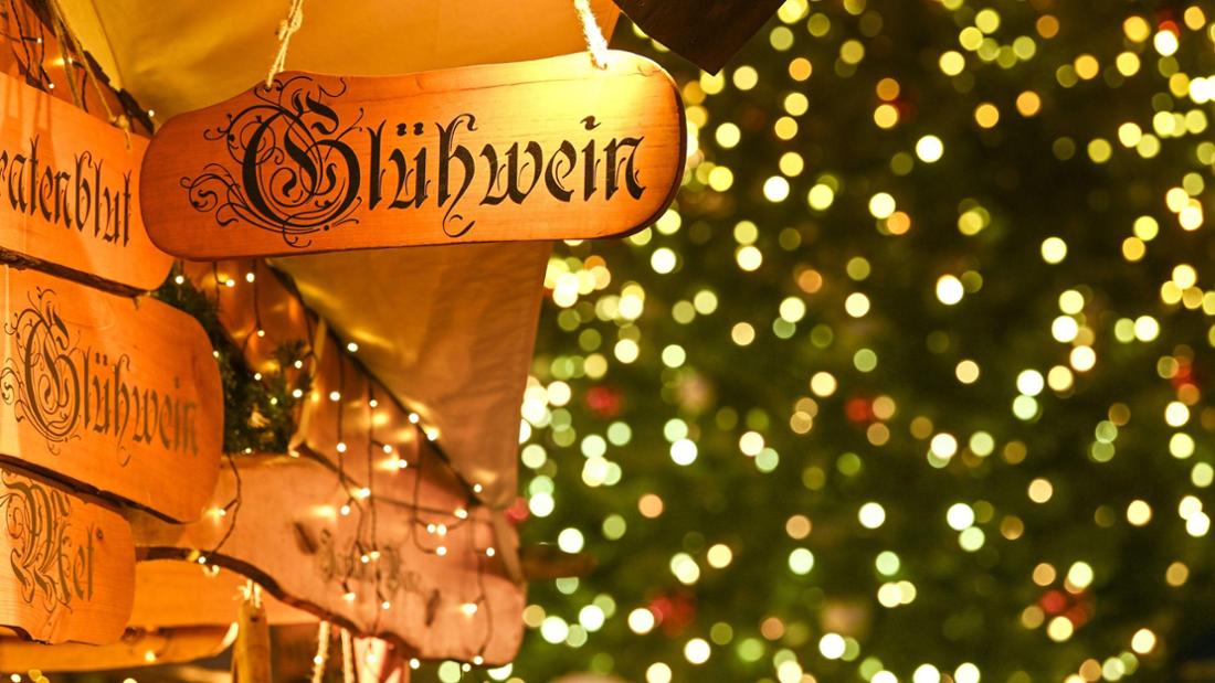 Ein Holzschild mit der Aufschrift „Glühwein“ hängt auf dem Weihnachtsmarkt