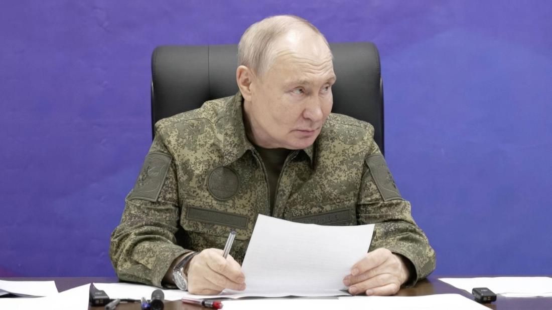 Wladimir Putin sitzt in Militärkleidung an einem Tisch und hält Stift und Papier in der Hand