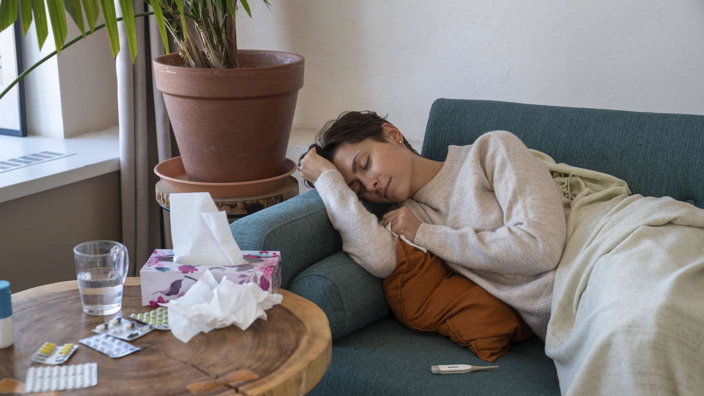 Frau liegt krank auf dem Sofa