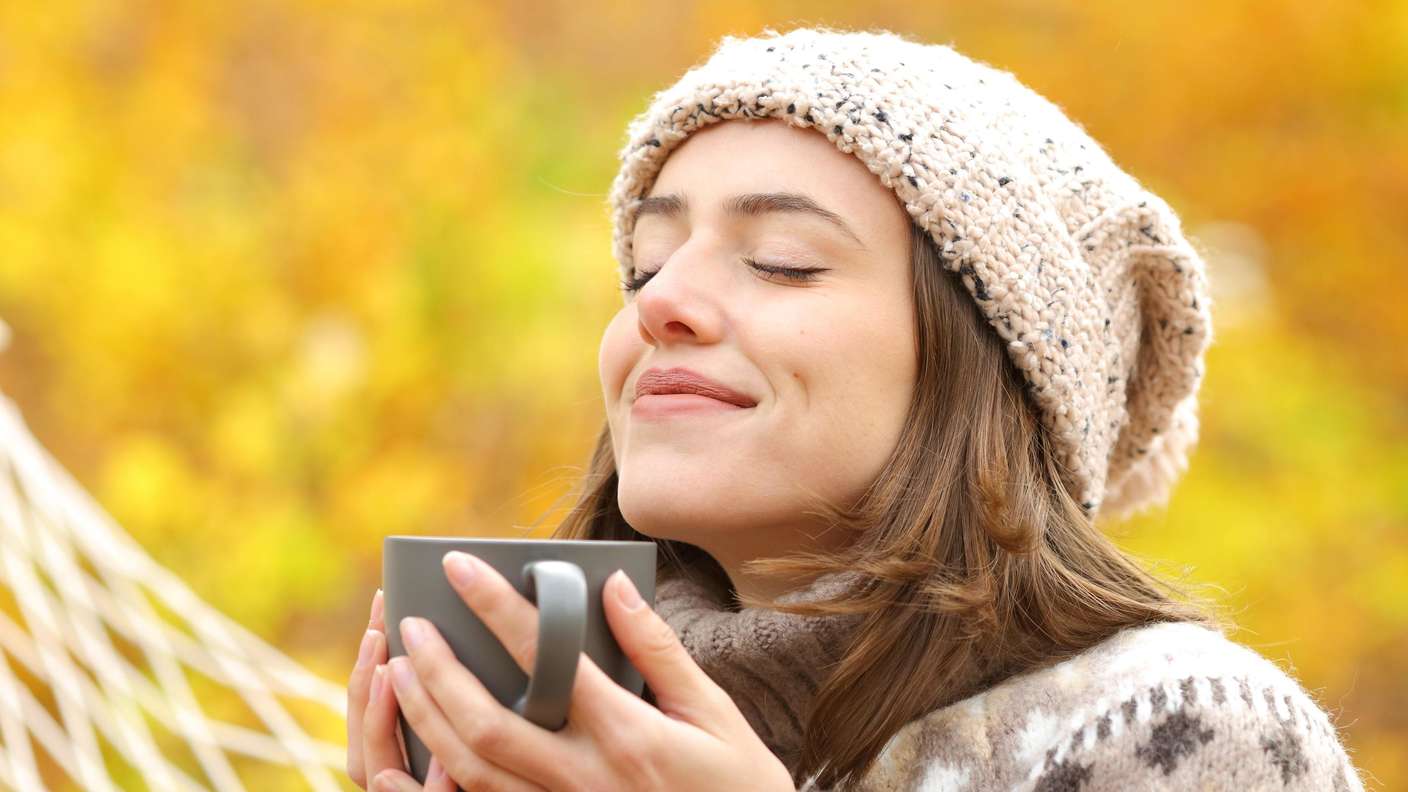 Eine Frau atmet tief ein und trinkt einen Tee. 