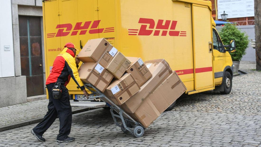 Ein DHL-Paketbote lädt eine Vielzahl an Paketen aus seinem Auto