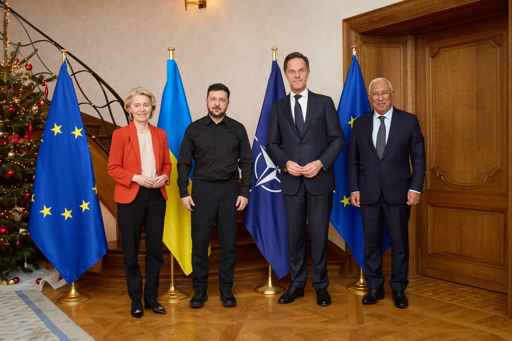 Präsidentin der Europäischen Kommission Ursula von der Leyen, Präsident der Ukraine Wolodymyr Selenskyj, NATO-Generalsekretär Mark Rutte und Präsident des Europäischen Rates Antonio Costa posieren bei einem Treffen in Brüssel am 8. Dezember 2025 vor EU-, NATO- und ukrainischen Flaggen.