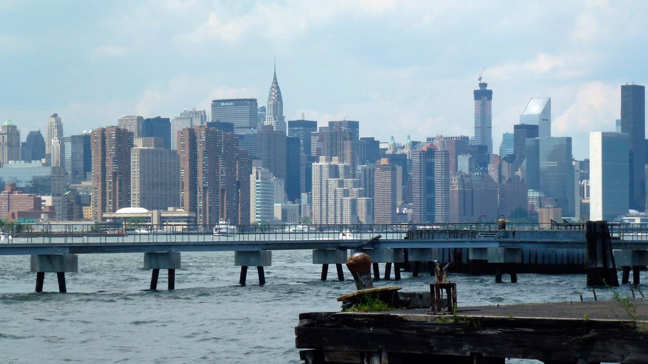 Blick auf den East River mit Manhattan im Hintergrund, aufgenommen vom Ufer in Williamsburg, Brooklyn, New York am 22.06.2014
