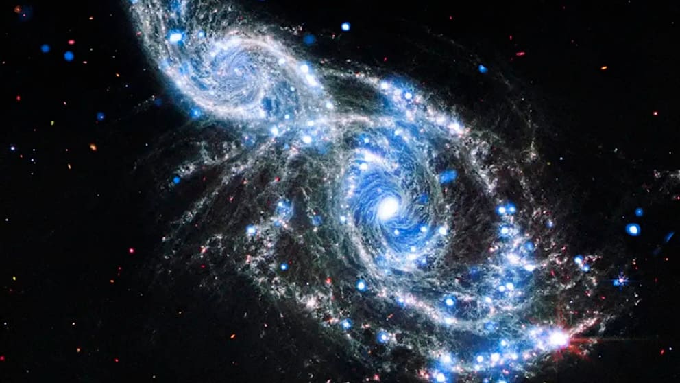 In einem gewaltigen Farbenschauspiel verschmelzen die Galaxien