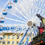 Ein Nikolaus mit Geschenken sitzt beim Weihnachtsmarkt in Duisburg auf dem Dach einer Glühweinhütte.