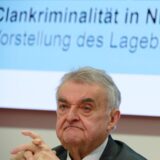 NRW-Inneminister Herbert Reul sitzt auf einer Pressekonferenz in Düsseldorf vo einer Leinwand, auf der der Schriftzug Clankriminalität zu sehen ist.